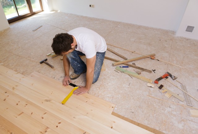 man-measuring-wood-flooring-in-new-house-SBI-305128259.jpg